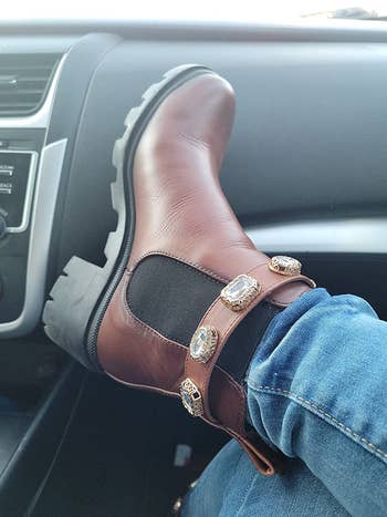 a reviewer wearing brown steve madden ankle boots with jewels around the ankle