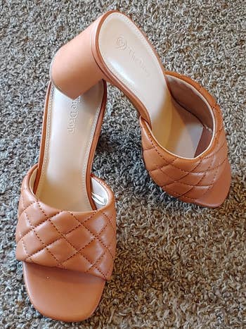 Pair of quilted open-toe heeled mules on a textured surface, suitable for a stylish outfit