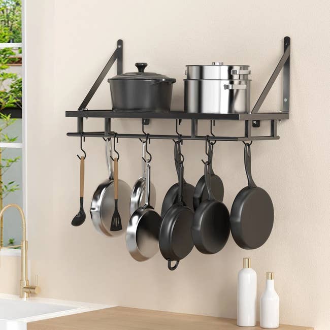 Wall-mounted kitchen rack with pots and pans. Hooks hold utensils and cookware. Suitable for organizing and saving counter space