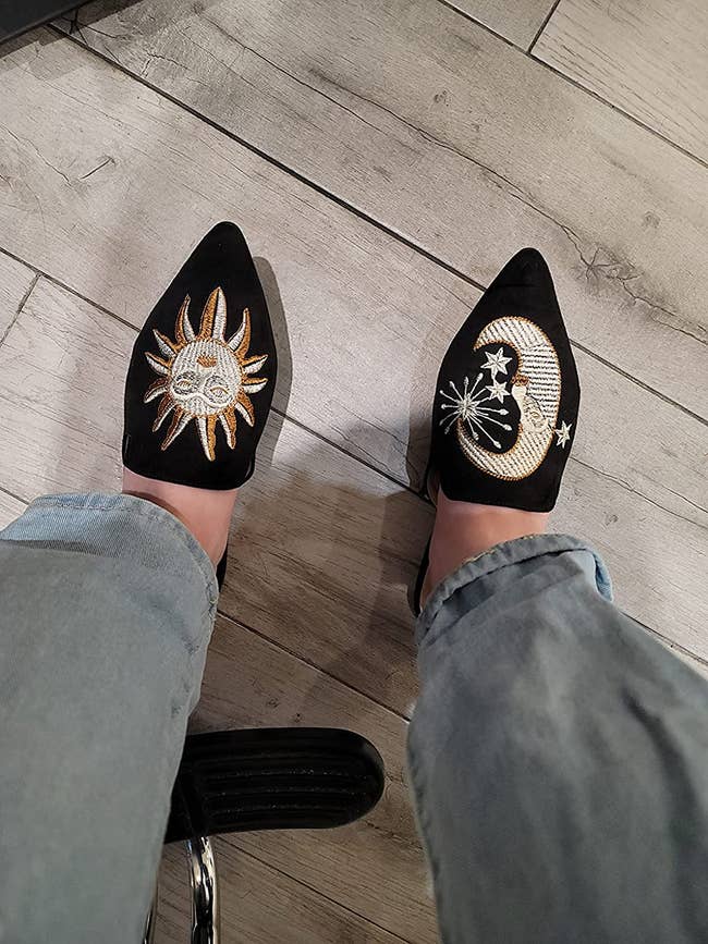 model in black flats with large sun embroidered on one foot and moon on the other