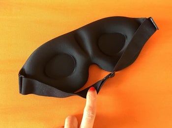reviewer showing the inside of the eye mask and how it's contoured to fit the eyes