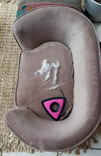 Plush favored furniture with a grooming instrumentality and clumps of favored fur connected it, placed connected a woven rug adjacent to a works and a footstool