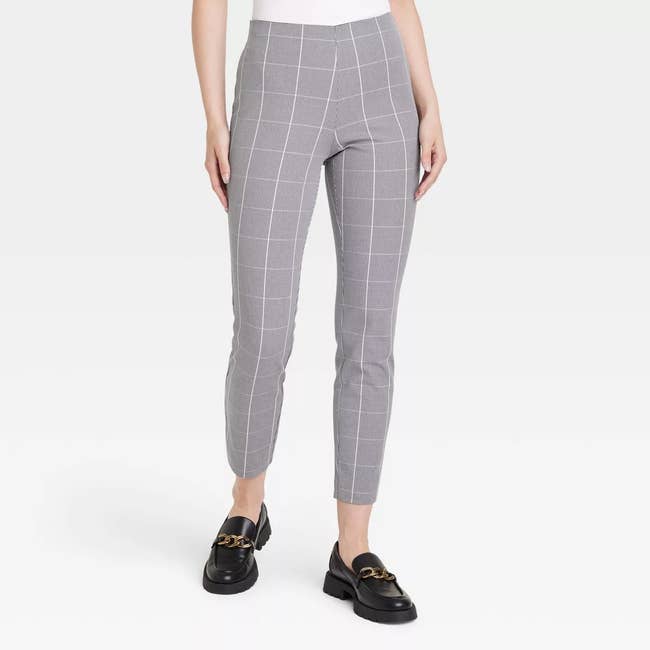 a model wearing the pants in gray featuring a white windowpane plaid 
