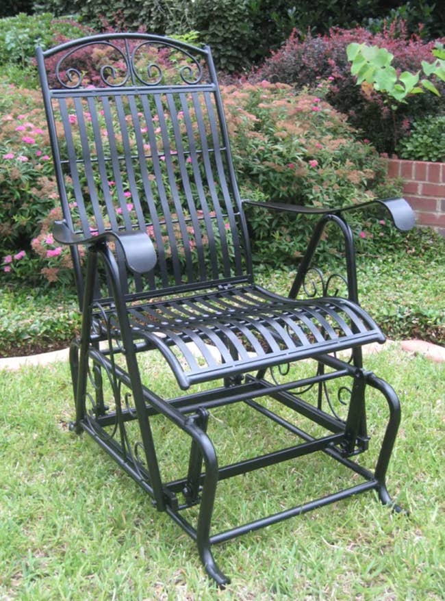 Curved wrought iron gliding chair standing on grass outside