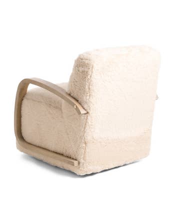 Elegant fluffy armchair with woody armrests viewed from the back, showcasing its plush texture and modern design