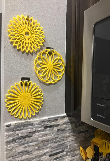 three yellow flower trivet mats hanging on a wall