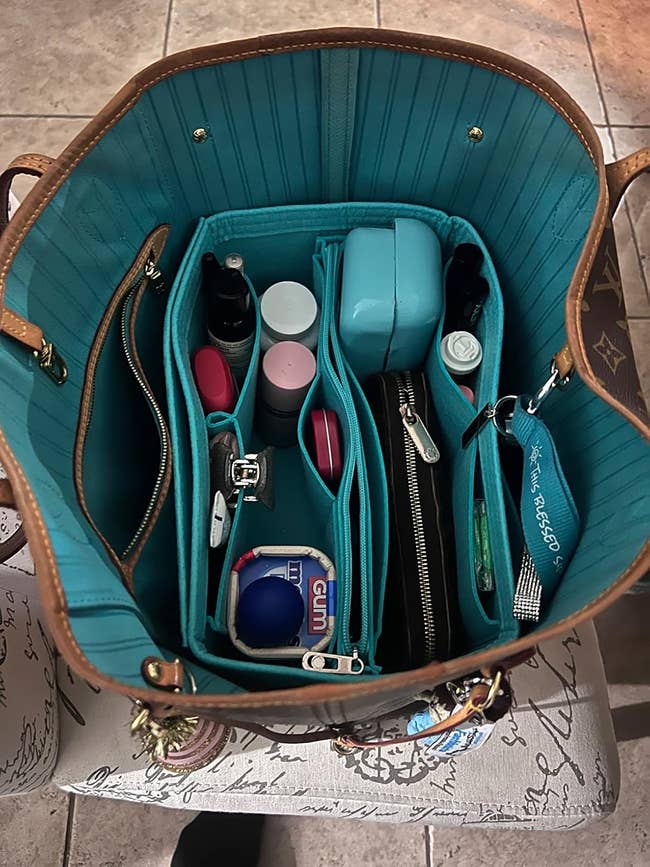 A well-organized handbag interior showcasing a variety of personal care and tech items, neatly placed in a compartmentalized bag organizer