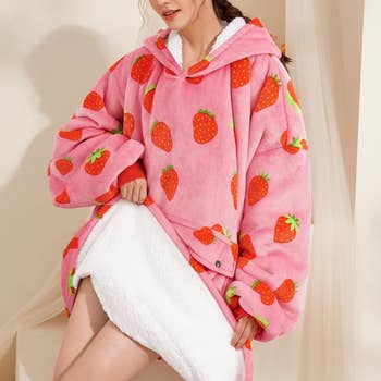 the strawberry blanket hoodie on a model, who is showing the fleece lining
