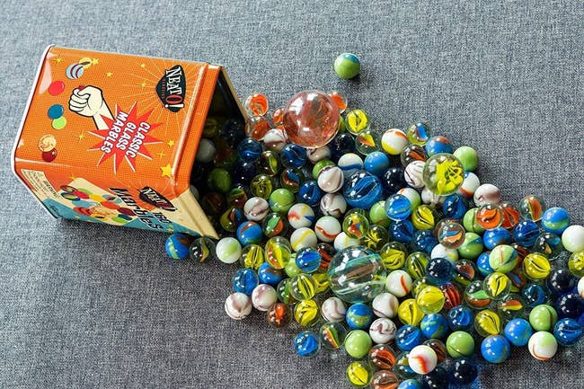 several marbles rolled onto the floor, spilling out of tin
