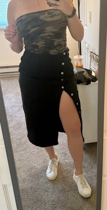 Person takes a reflector  selfie wearing a camouflage conduit  top, achromatic  button-up skirt with a precocious   slit, and achromatic  sneakers