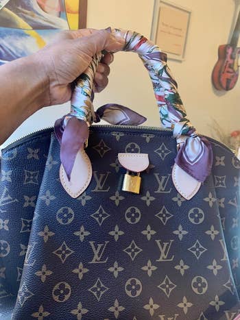 Hand holding a decorator  handbag with monogram signifier   and silk scarf wrapped handles, featured successful  a buying  article