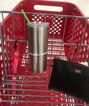 a reviewer photo of a tumbler cup in the cup holder that''s mounted on a Target cart 