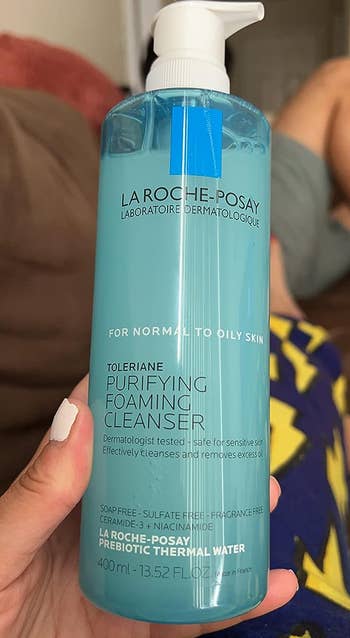 reviewer holding bottle of cleanser 