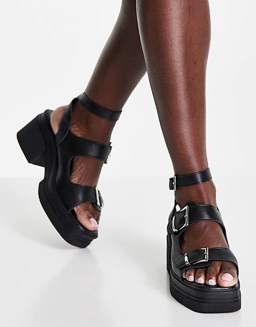 model wearing the black buckled platform sandals