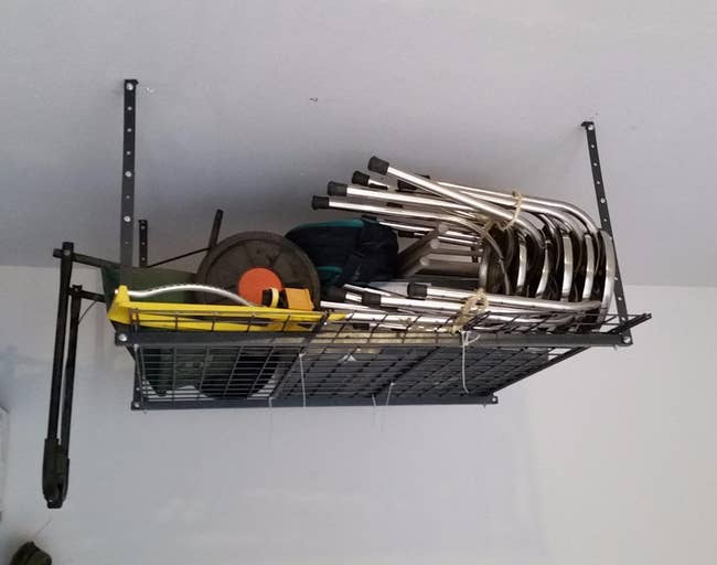 Overhead retention support successful a store holding folded chairs, a yellowish box, and assorted tools