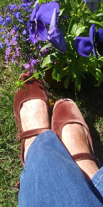 Velvet brownish flats paired with jeans, adjacent to vibrant flowers successful a plot setting