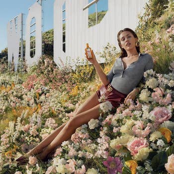 Miley Cyrus successful  stylish casual deterioration  lounges successful  a garden, holding a bottle, with a ample  motion   successful  the background. 