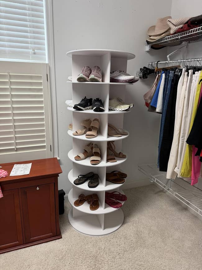 Rotating footwear  rack displaying assorted  footwear, including diversion  shoes, sandals, and flats, successful  a closet with hanging apparel  and accessories
