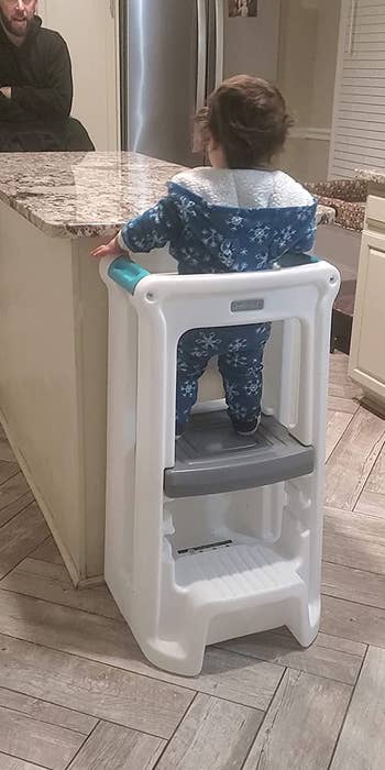 A child standing in the tower to reach a table