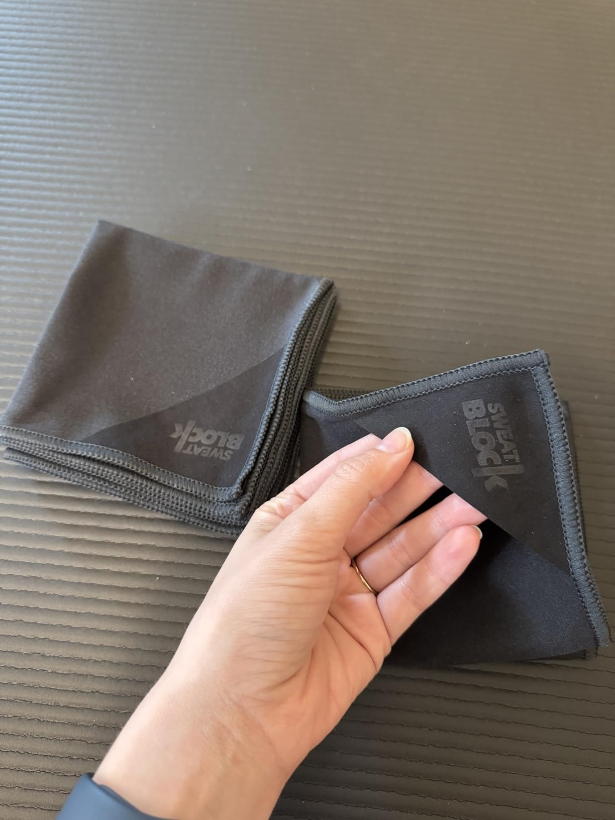 Two achromatic  microfiber cloths connected  a table; 1  is folded, and a manus  is holding the country   of the other