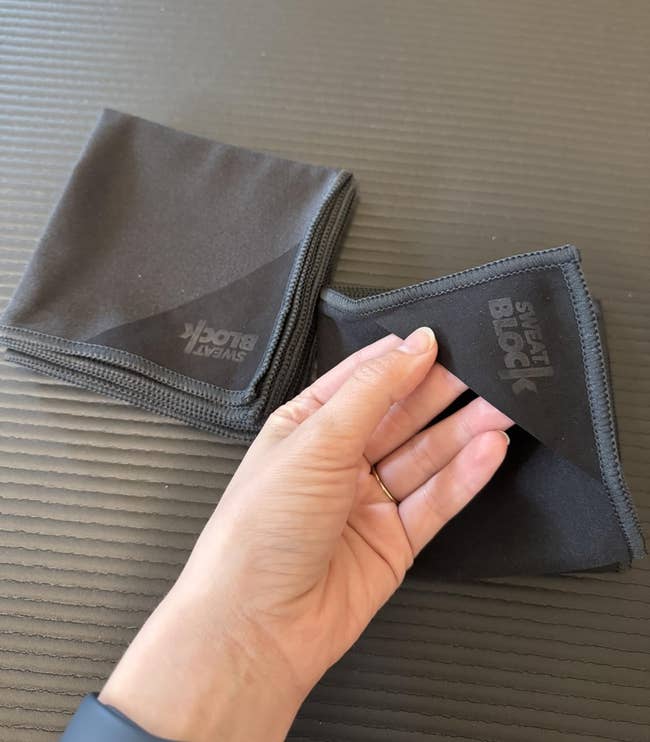Two achromatic microfiber cloths connected a table; 1 is folded, and a manus is holding the country of the other