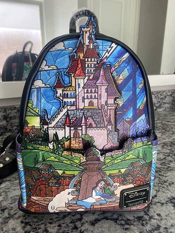 a beauty and the beast backpack with a stained glass design on it