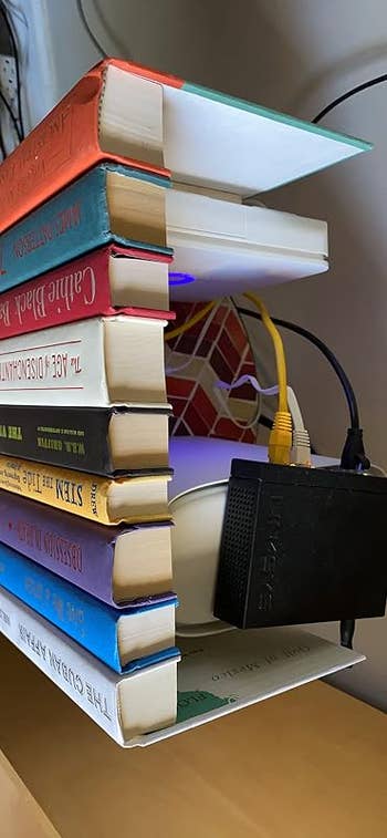 Wi-Fi router hidden wrong   a vertical stack of heavy   hardcover books connected  a shelf