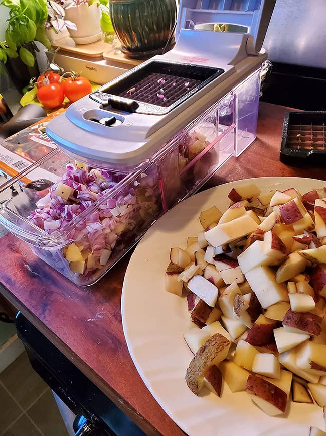 reviewer's veggie cutter filled with chopped red onion next to a plate of chopped red potatoes