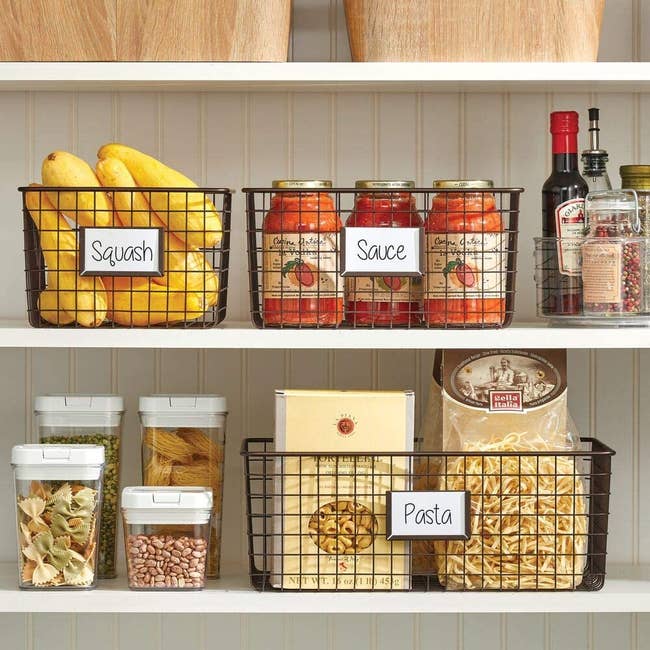 three baskets in a pantry holding pasta, sauce, and squash