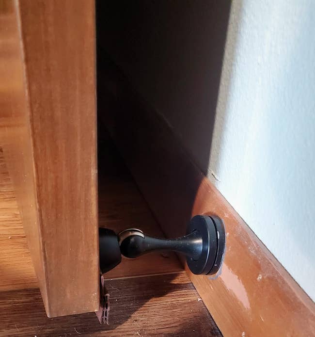 A doorstopper holds a doorway  ajar, preventing it from swinging closed. The mounting  is indoors, showcasing elemental  location  hardware functionality