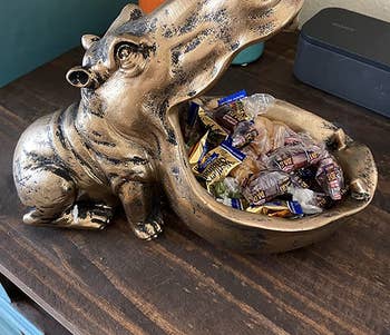 reviewer photo of the gold hippo candy dish holding candy in its mouth