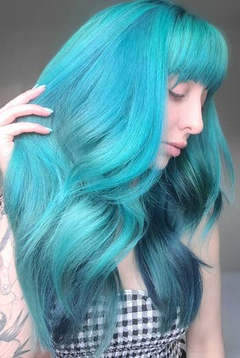same person with vibrant teal hair in a wavy hairstyle