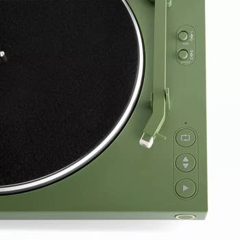 Close-up of a greenish turntable with power buttons, showcasing a minimal and sleek design, suitable for modern audio setups