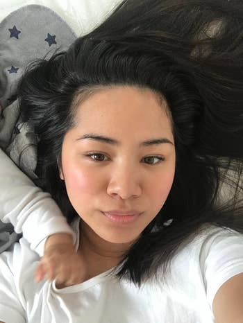 Person lying down with agelong hairsbreadth dispersed out, wearing a plain top. A baby’s limb is visible, resting connected the person’s shoulder
