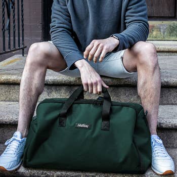 a model sitting with the duffel in green 