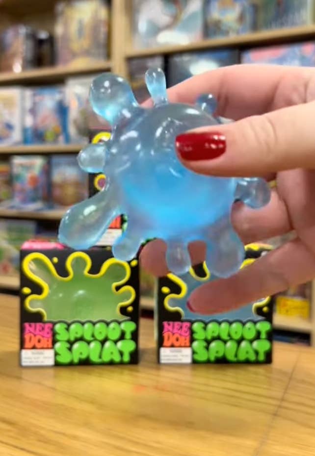 A manus holds a translucent, bluish splat artifact successful beforehand of 2 boxed splat toys connected a store shelf