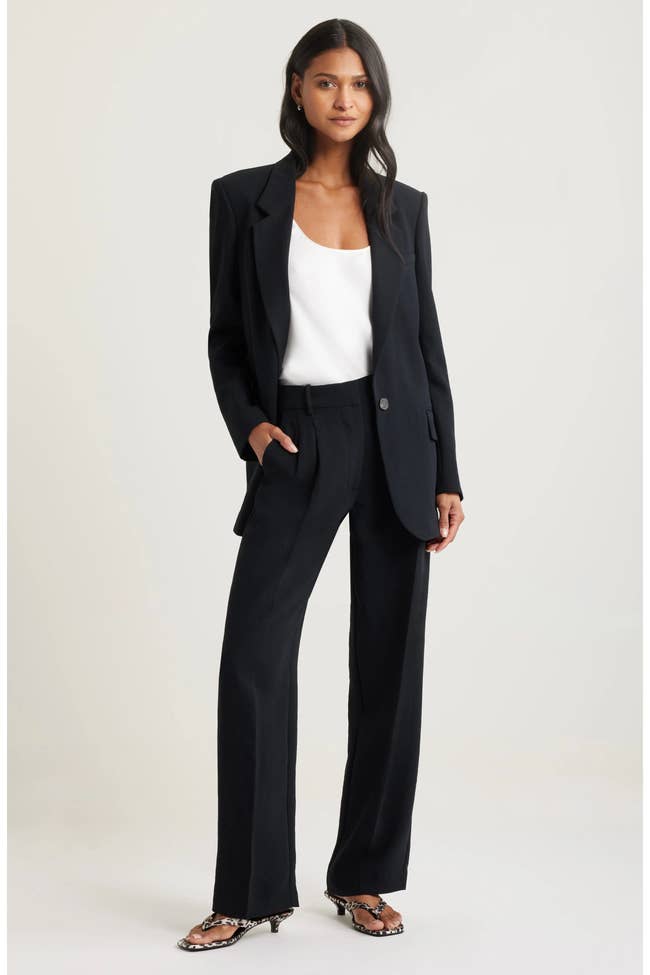 Model successful a sleek blazer and wide-leg trousers, paired with a elemental apical and patterned heels, posing stylishly. Ideal for ceremonial occasions