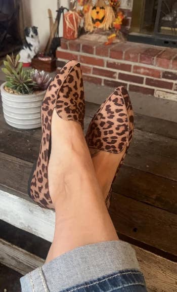 Person wearing leopard print high-heeled shoes crossed at the ankle