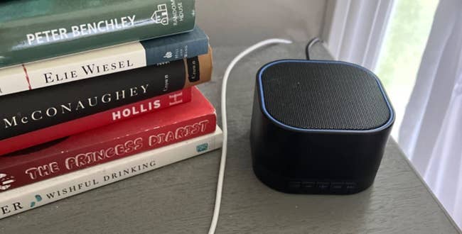 white noise machine on a table next to a stack of books