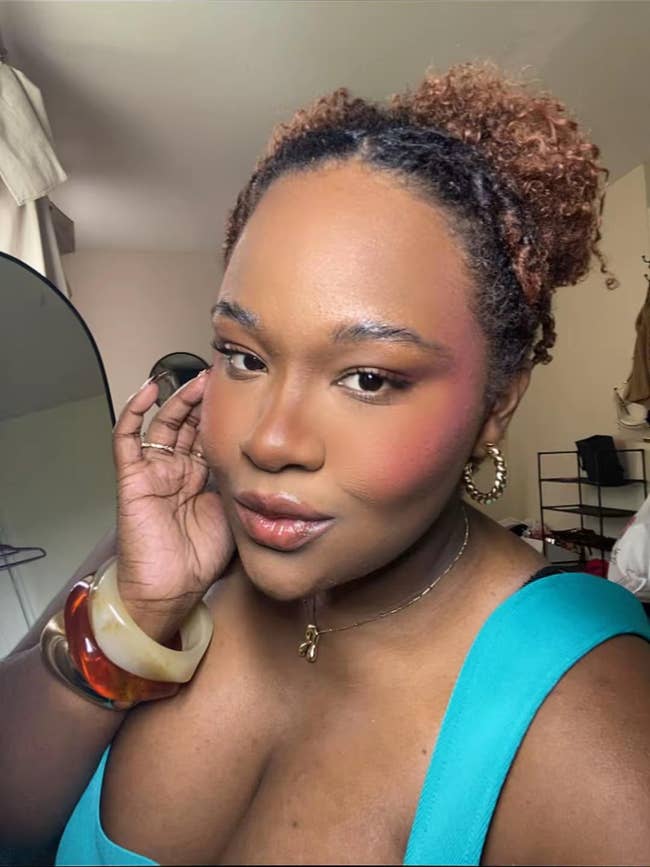 Person wearing hoop earrings and bracelets, posing confidently indoors