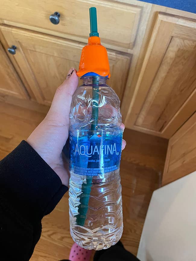 reviewer photo of the orange silicone piece on the mouth of an aquafina plastic water bottle