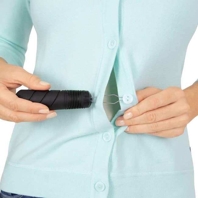 a model using the dressing aid tool to button their shirt
