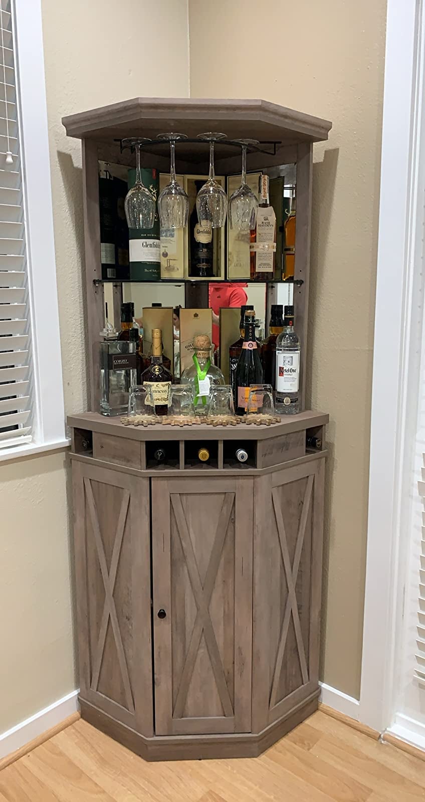 Brown wooden and glass corner cabinet with alcohol and glasses inside