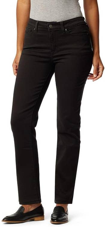 A person wearing black jeans and black loafers.