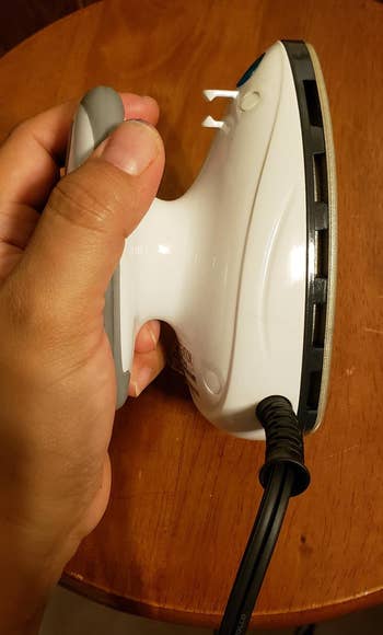 reviewer holding the mini iron to the side, showing how small it is
