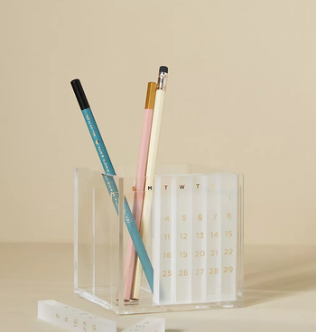 the acrylic pen holder with some of its numbered sticks inside of the built-in calendar space and some in front