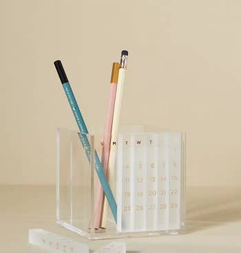 the acrylic pen holder with some of its numbered sticks inside of the built-in calendar space and some in front