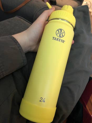 reviewer holding larger yellow bottle