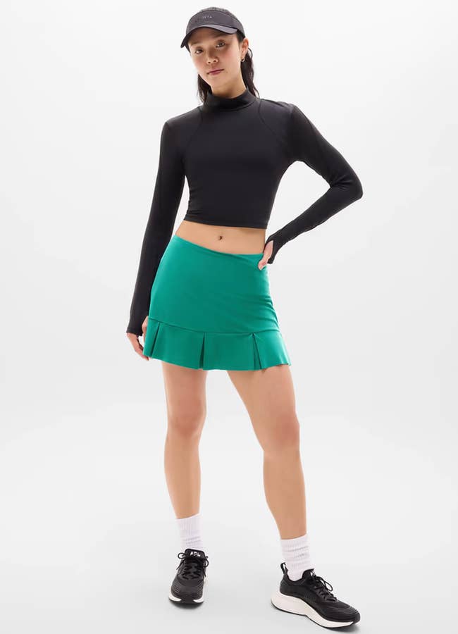model successful a sporty outfit with a long-sleeve top, pleated skirt, and cap, lasting confidently, perfect for diversion oregon casual wear