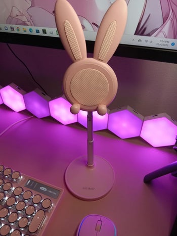 Bunny-shaped desktop fan next to a keyboard and mouse, with hexagonal lights in the background
